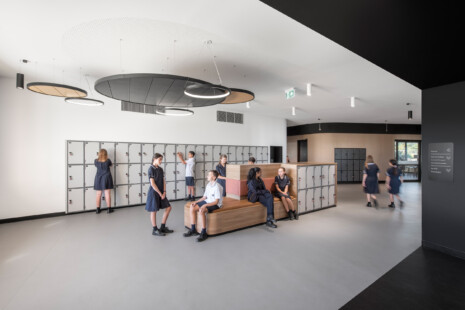 Glenunga International High School Learning Building's 'learning street' winds students past drink fountains, lockers, and modular furniture and creates space to interact with each other between classrooms. The black and white interior is softened with curving timber cladding and large circular feature lighting.